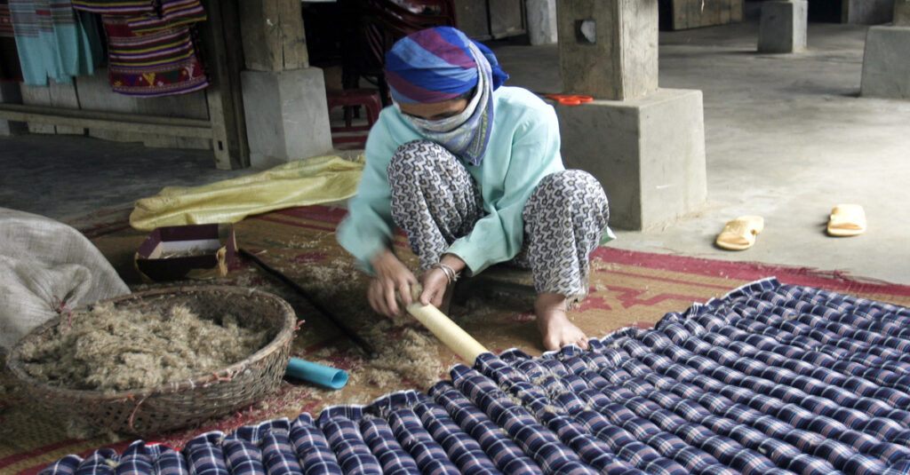 Imagen de una mujer en Mai Chau fabricando un colchón