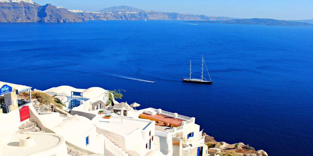 Un crucero surca el mar junto a un pueblo de Grecia