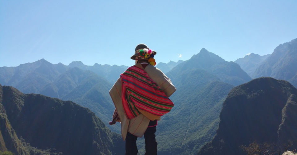 persona-poncho-andes Miembro de una comunidad andina de Perú contemplando el horizonte desde una montaña