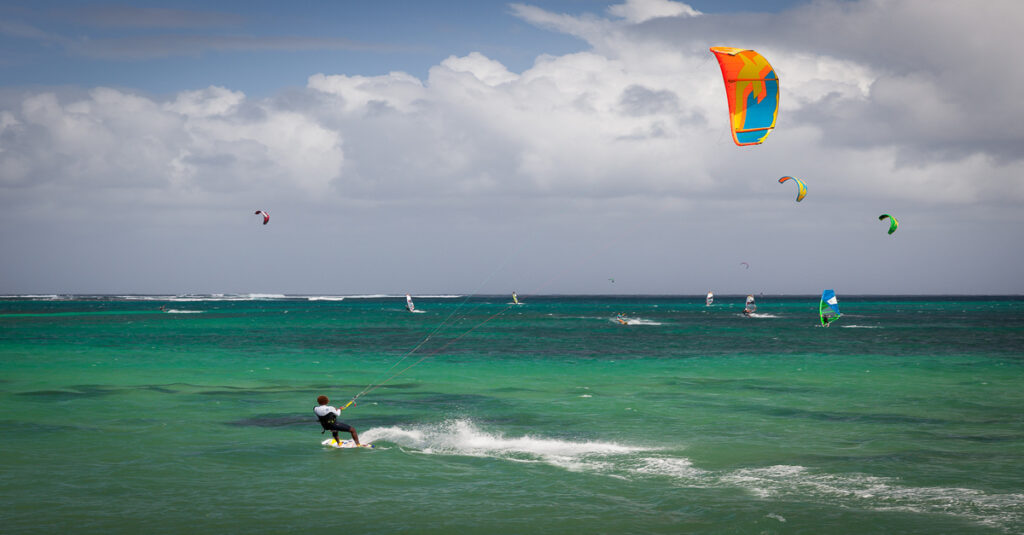 Gente practicando kitesurf en una playa de Le Morne