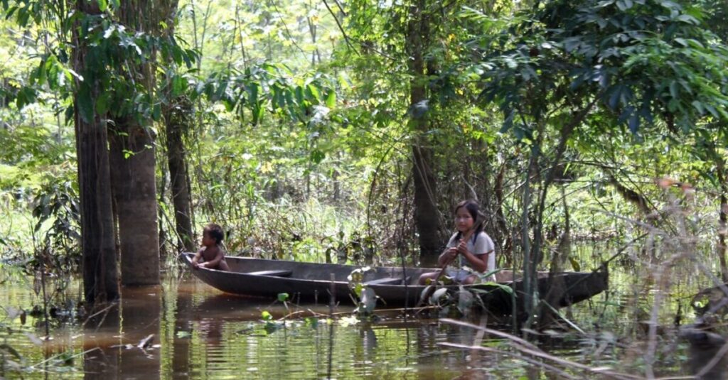 Niños de una comunidad indígena amazónica surcando un río en barca