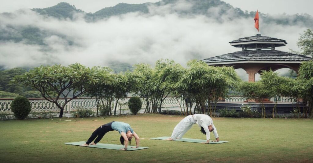 Gente practicando yoga en un monasterio de Rishikesh, junto a las montañas